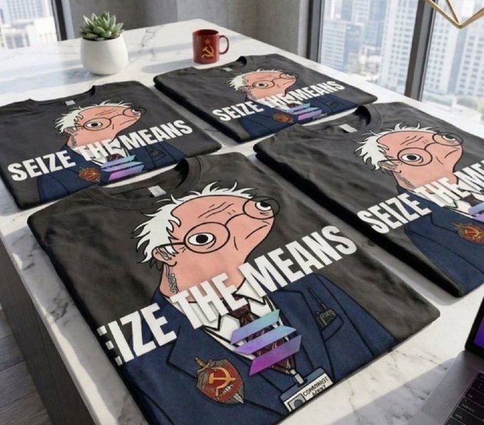 The image features a collection of t-shirts with cartoon characters, including a character named Bernie Sanders. The t-shirts are displayed on a table or countertop, showcasing their designs and colors. One of the t-shirts has "Seize the Means" written across it in white letters. The text also includes an image of a man wearing a suit and tie, which is likely related to the political theme of the t-shirt design.