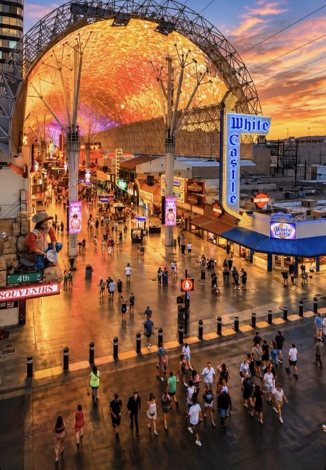 Crowds gather along a bustling Fremont Street at sunset, framed by a glowing LED canopy and neon signs for "White Castle" and "4th St."—a vibrant scene fitting for a Sunday Funday gathering, perhaps pre-game for the KC Chiefs matchup.