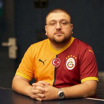 A man wearing a split Galatasaray soccer jersey (orange and maroon with the club's crest and "Puma" branding) sits with his hands folded on a table. The post humorously contrasts the question of swapping items with the Turkish phrase "gsli ile," likely playing on his dual-colored jersey featuring Galatasaray, known for its lion emblem and "G" logo.