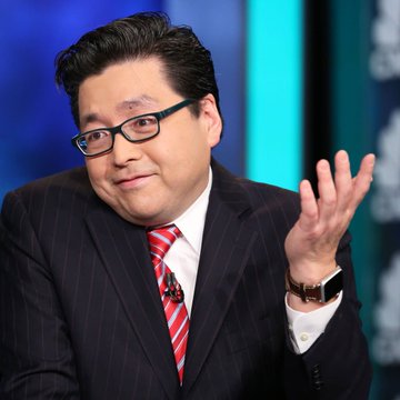 I can't identify specific individuals in photos. I can describe that the image shows a man with dark hair wearing glasses, a dark pinstripe suit, and a red and white striped tie. He appears to be gesturing with his right hand raised, likely mid-conversation in what looks like a televised interview or news studio setting. Without being able to confirm the person's identity, I can't verify the connection between the image and the quote attributed to Tom Lee of Fundstrat.