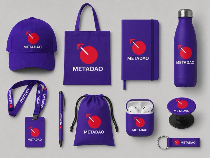 A branded merchandise collection for "METADAO" featuring purple items—including a cap, tote bag, notebook, water bottle, lanyard, pen, AirPods case, PopSocket, keychain, and drawstring pouch—each displaying a red flag logo and the word "METADAO," suggesting a promotional tie-in to the $META token.