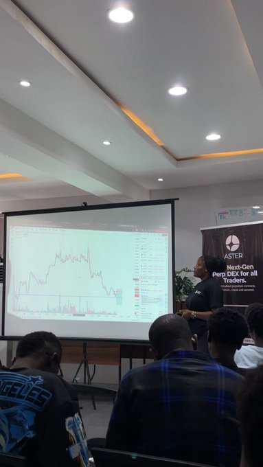 A presentation at an 'ASTER' event promoting a 'Next-Gen Perp DEX for all Traders,' with a speaker displaying a chart on a projector screen to a seated audience.
