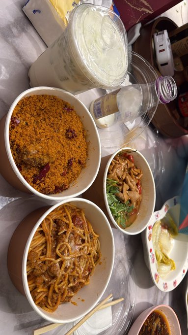 A spread of takeout dishes including noodles, a bowl of rice with red toppings, and what appears to be meat with greens, accompanied by empty takeout containers and chopsticks, likely ordered from "Socks" as mentioned in the caption.