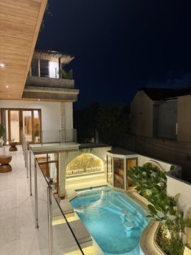 A luxurious modern villa at night features an illuminated outdoor pool with a cascading water feature, sleek wooden architecture, and tropical landscaping, paired with the caption celebrating how Web3 has facilitated genuine real-life connections and friendships.