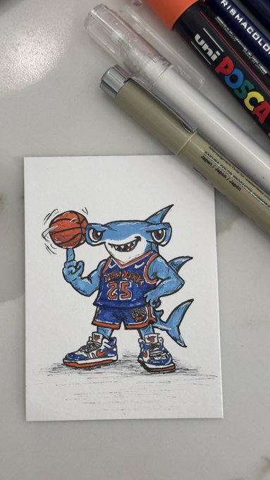 A small ink and marker illustration depicts a cartoon shark wearing a blue New York Knicks jersey (#23) spinning a basketball on its finger, placed next to Uni Posca markers on a desk.
