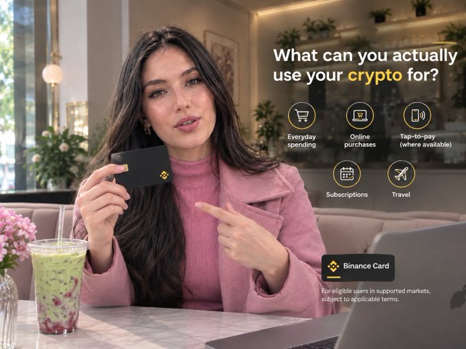 The image shows a woman holding a Binance Card while sitting in a café, pointing to it as the accompanying text highlights the question "What can you actually use your crypto for?"—with icons illustrating everyday spending, online purchases, tap-to-pay, subscriptions, and travel, tying directly to the post's message about exploring crypto for real-world use.