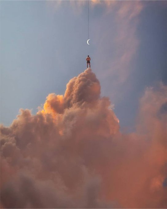 A person stands triumphantly atop a towering cloud, reaching toward a crescent moon suspended by a thread in the sky. This surreal scene perfectly complements the "GOOD MORNING FAM" greeting, evoking a dreamy, aspirational start to the day.
