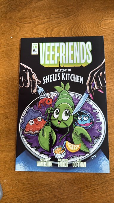 A physical comic book titled 'VEEFRIENDS WELCOME TO SHELLS KITCHEN' issue 18, featuring colorful cartoon characters including a pea, a tomato, and an oyster around a plate, with names Gary Vaynerchuk, James Patrick, and JR Goffman at the bottom.