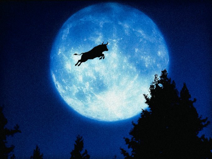 A silhouette of a bull leaping dramatically across a large, glowing blue full moon with dark treetops visible in the foreground.
