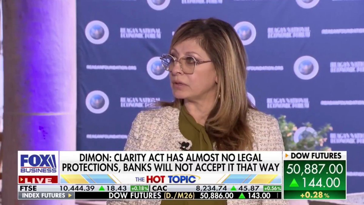 The image shows a woman wearing glasses sitting at a desk with her face on a TV screen. The TV screen displays an advertisement for a product, and there are several logos visible around the room. The text on the screen reads "BANKS ARE SCARED AND JAMIE DIMON JUST ADMITTED IT" which is related to the post about banks being scared of the Clarity Act.