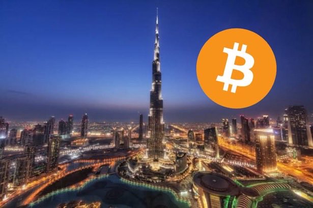 Nighttime skyline of Dubai featuring the Burj Khalifa, with an overlaid orange Bitcoin logo in the upper right corner.