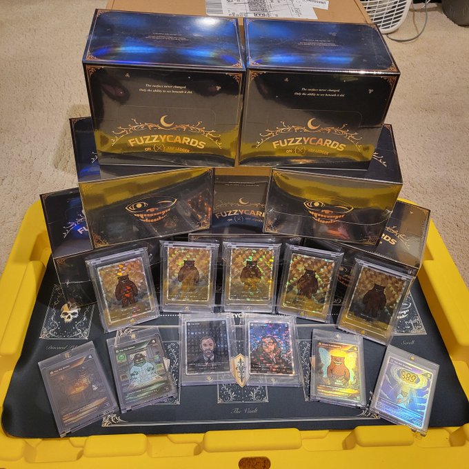 Collection of FuzzyCards trading card sets and individual holographic character cards displayed on a yellow case, including monster, ghost, and warrior-themed cards.