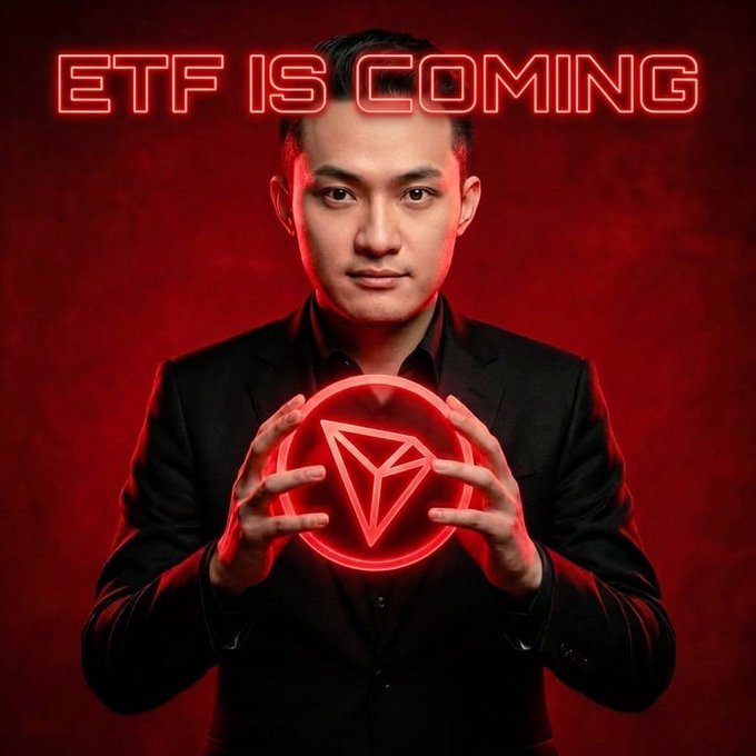 A promotional image featuring a man in a dark suit against a red background, holding a glowing red triangular symbol, with the neon text "ETF IS COMING" above him.