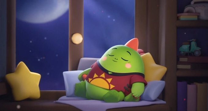 A 3D animated green character with a small pink mohawk wearing a red shirt with a yellow sun design, sleeping peacefully on a windowsill with star pillows against a night sky background.