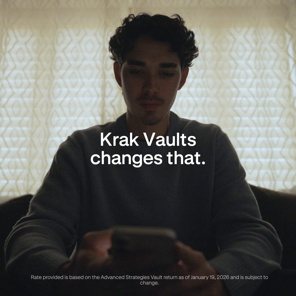 The image shows a person sitting down using their phone while reading an advertisement for a cryptocurrency service called Krak Vaults. The advertisement promotes a Bitcoin trading platform that offers a 2.5% APY, with no minimum deposit required and the ability to access funds at any time via Bitcoin Cash. This text is presented in large white letters below the image, making it more visible as the viewer reads through the content of the advertisement.