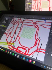 A photo of a computer monitor displaying a red-lined digital drawing or map with a green square pattern in the center.