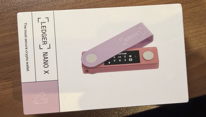 A pink Ledger Nano X, the most secure crypto wallet, displayed on its white product box with the lanyard attached to the device.