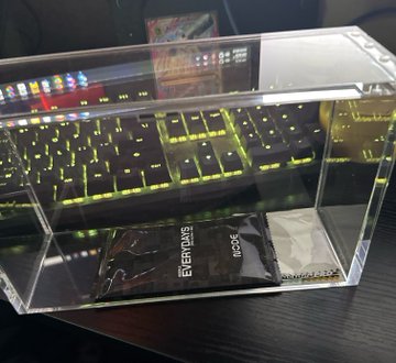 The image features a clear case with two sealed bags inside, placed on a table or countertop. The case appears to be made of glass, providing a sleek appearance for its contents. One of the bags contains a white paper, possibly containing important information related to the trading cards being discussed in the post. It seems like there's been some kind of trade recently, as evidenced by the text provided in the image.