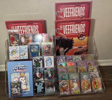 A store display of trading card game merchandise featuring sealed 'VEEFRIENDS' booster packs and opened display boxes showing colorful creature cards, with 'PIX PERROS & POPS' branding visible.