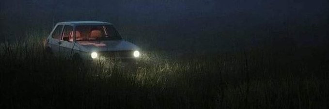The image features a white car driving through a field at night with a dark sky overhead. The car's headlights are shining brightly, illuminating its path as it moves across the scene. In the background, there is a river flowing strong, adding an element of natural beauty and tranquility to the overall atmosphere.
