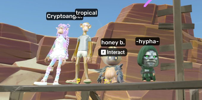 A screenshot from a video game or virtual world shows four 3D avatars standing on a wooden platform in a desert-like environment, with username tags 'Cryptoangi', 'tropical', 'honey b.', and '-hypha-' displayed above them, along with an 'Interact' prompt.