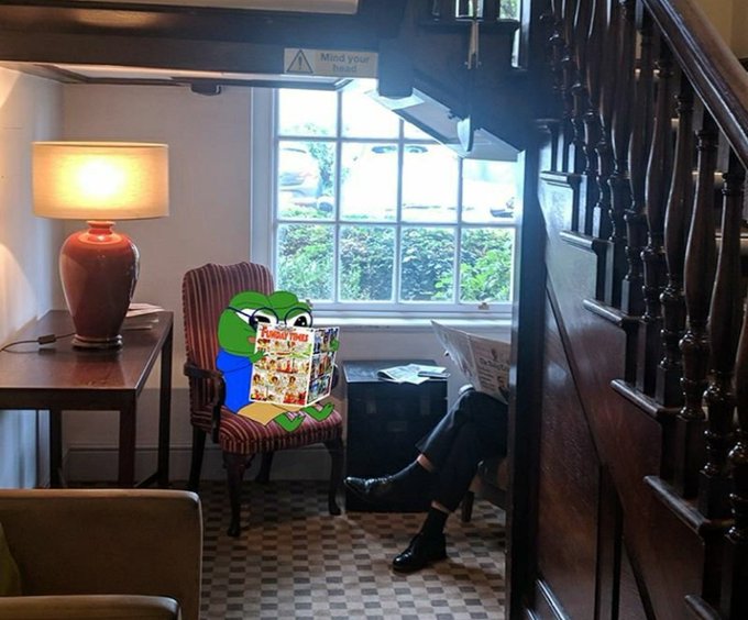 The image features a cartoon frog sitting in an office chair, reading a newspaper or magazine while looking out of a window. The room has wooden furniture, including chairs and tables, creating a cozy atmosphere. A lamp can be seen near one of the chairs, providing additional lighting for the space. The post includes a link to a website called @wallchain, which is likely related to web3 technology or blockchain.