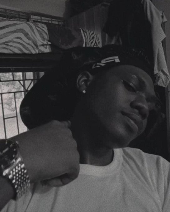A black-and-white selfie shows a young man wearing a "LV" headband, with a bunk bed and zebra-print pillows visible in the background behind him. The caption "Good morning Frens I'm so under the weather" reflects his tired expression, while the mention of @wolfswapdotapp pairs with the "LV" branding in the image.