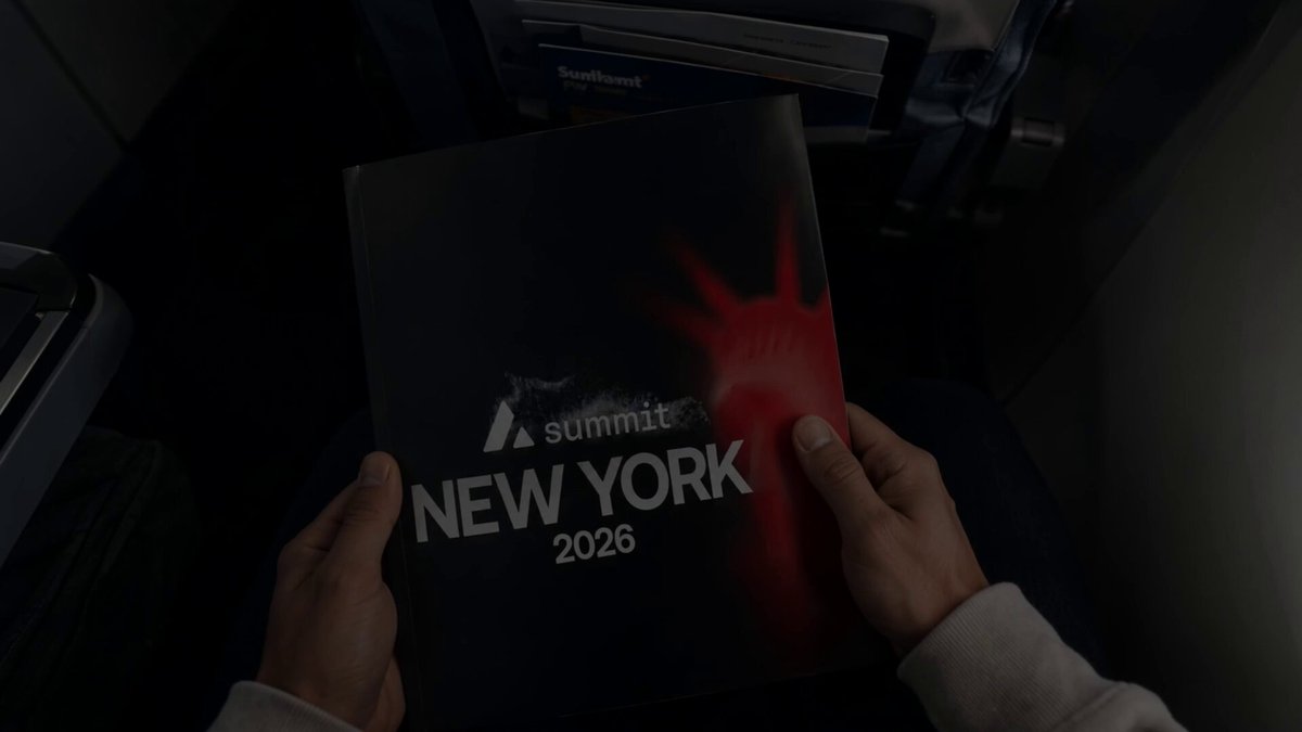 The image shows a person holding up a book titled "New York 2026" with red text, which appears to be a summary or description of an event happening in New York City. The person's hands are visible as they hold the book open, showcasing its content and possibly drawing attention to it. The post is about an upcoming summit that will take place in NYC, where people can join friends and community members for a meeting with Avalanche Summit.