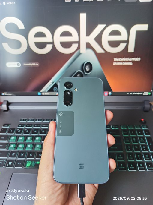 A hand holds up a teal-colored Seeker phone (labeled "SEED VAULT") in front of a monitor displaying the Seeker branding as "The Definitive Web3 Mobile Device," with the photo watermarked "artdyor.skr Shot on Seeker" and dated 2026/09/02 08:35. The image showcases the Solana Seeker device in action, visually reinforcing the post's claim that it's the best Web3 mobile available.
