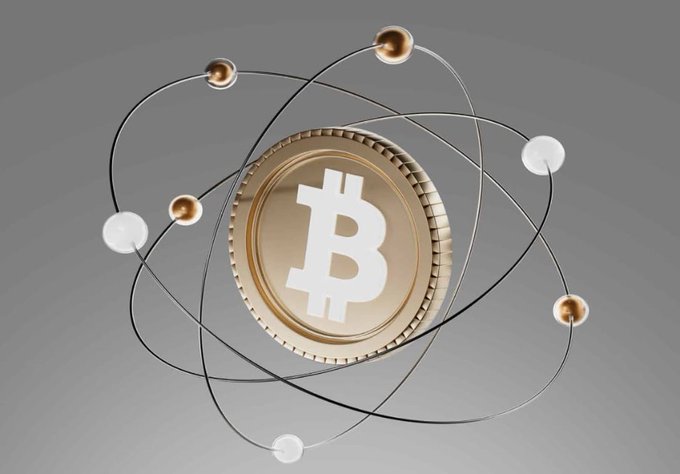 A 3D rendering of a gold Bitcoin coin surrounded by orbiting electrons and atomic orbits, set against a gray background.