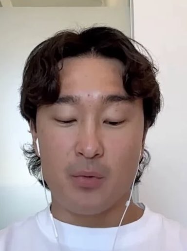 The image shows a man with curly dark hair wearing white earbuds and a white shirt, looking downward with a slight smile. 

Note: The caption doesn't appear to match the image—the person shown is not playing basketball, and there are no orangutans ("Orangie") or other individuals ("Threadguy") visible. The image appears to be a simple selfie-style shot that doesn't visually correspond to the described scene of playing basketball.