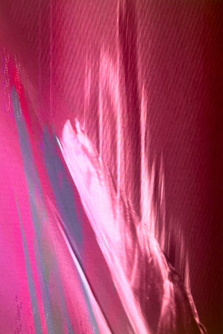 An abstract, blurry pink and magenta image with streaking light effects, possibly a photograph taken with intentional camera motion.