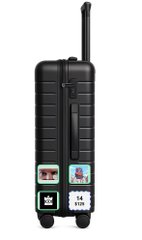 A small black hard-shell suitcase or equipment case with several stickers, including 'M 6' and what appears to be shipping labels.
