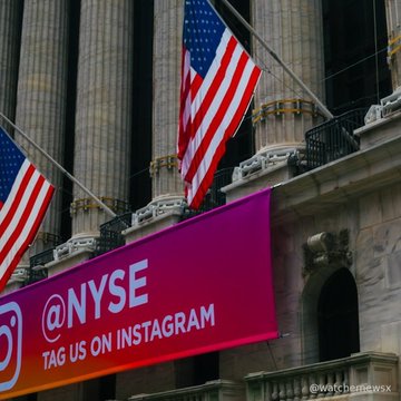 An American flag hangs from a columned building above a pink-to-orange gradient sign reading '@NYSE / TAG US ON INSTAGRAM.'
