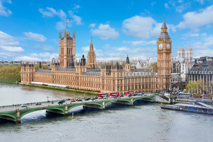 The Palace of Westminster and Big Ben overlook the River Thames in London, England. The image relates to the post as it depicts the UK government buildings, symbolizing the political tension between the country's ambition to become a global crypto hub and the banking sector's reluctance to serve crypto firms.