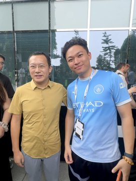 Two men posing for a photo, one wearing a yellow shirt and the other in a light blue 'Etihad Airways' jersey.