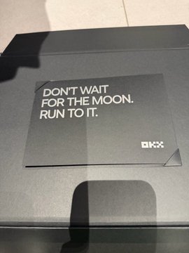 A gray OKX-branded Mid-Autumn Festival gift box is shown with a card reading "DON'T WAIT FOR THE MOON. RUN TO IT." and the OKX logo, suggesting the recipient received this themed promotional gift from the crypto exchange OKX, aligning with the Mid-Autumn Festival celebration mentioned in the post.