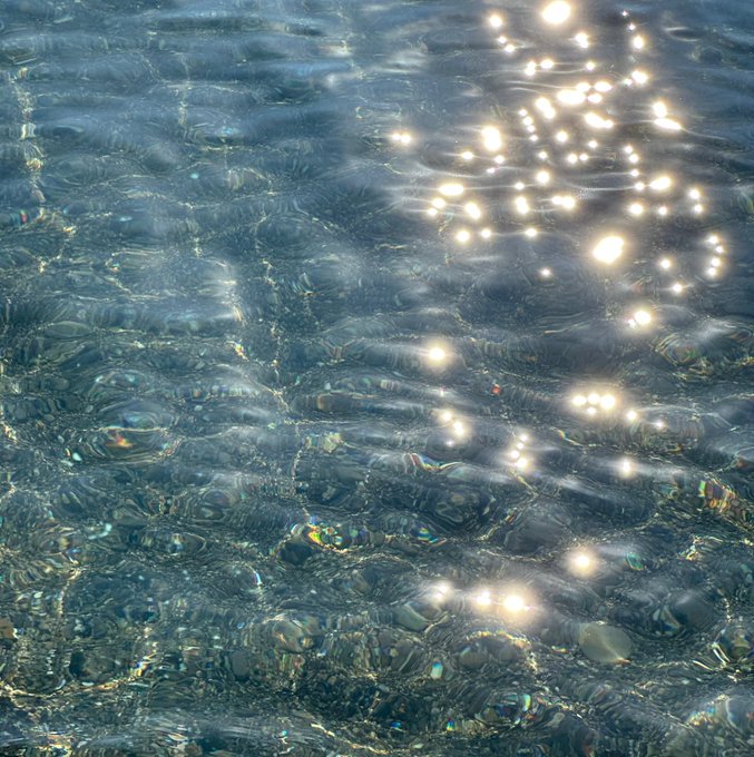 Sunlight sparkling and reflecting off the surface of clear, rippling water.