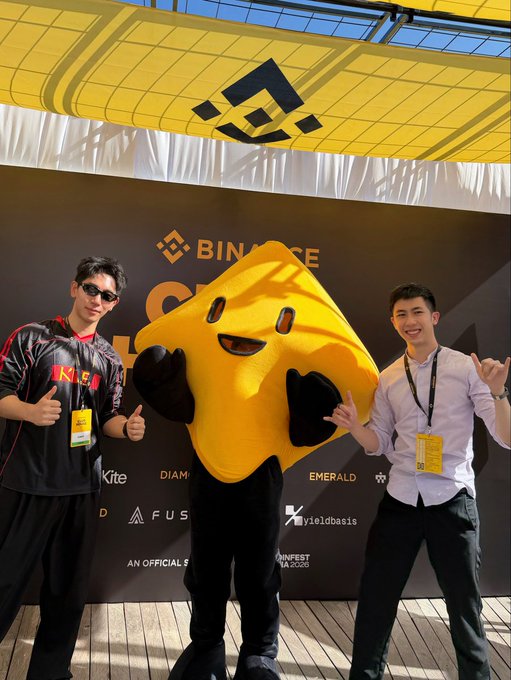 Two people pose with Binance's yellow mascot, "Bibi," at the Binance Club House during Coinfest, with "BINANCE" branding visible on the backdrop alongside partner logos including Kite, Diamond, Emerald, FUSION, and yieldbasis. The image captures the Kite AI team's participation as an event partner, matching the post's reference to attending Coinfest and working with the Binance marketing team.