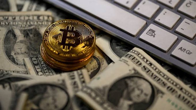 A gold Bitcoin token rests atop scattered U.S. dollar bills next to a keyboard, visually representing the surge of crypto investment highlighted in the post about Bitcoin whales accumulating over $2.9 billion in BTC within 60 days—a bullish signal for the crypto market.
