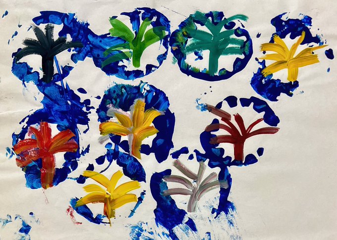 A child's painting featuring roughly eight blue circular stamps with hand-painted trees in various colors (green, yellow, red, brown) inside each circle on a white background.