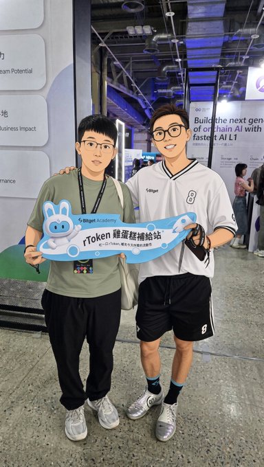 Two young men pose together indoors holding a sign that reads 'Token 鏈蛋糕補給站' alongside a cartoon rabbit logo; the man on the right wears a white jersey with the number '8', and banners in the background reference 'Building the next gen of on chain AI'.