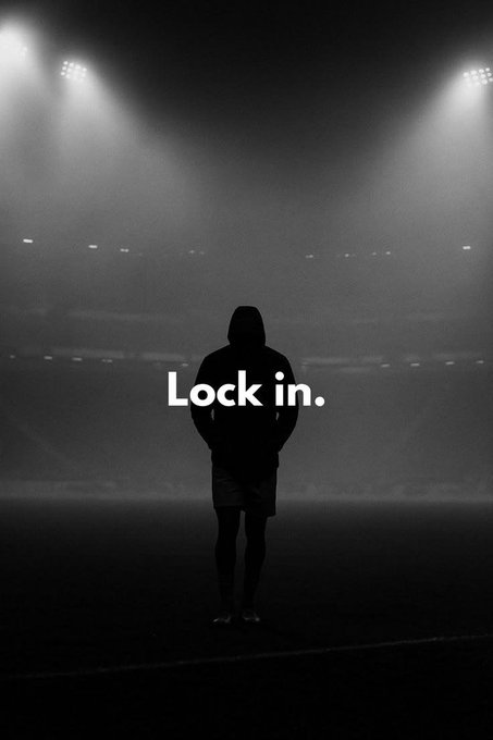 Black and white motivational image of a hooded silhouette standing in a stadium under spotlights with the text 'Lock in.' overlaid.