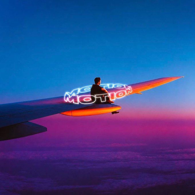 A person sits on an airplane wing above a vibrant purple and blue sunset sky, with glowing neon-style text reading "MOTION" floating beside them, visually echoing the post's enthusiasm for the $MOTION token on Solana.