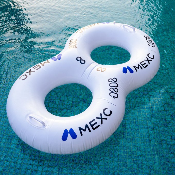 A white figure-eight inflatable pool float branded with 'MEXC' floats on the surface of a swimming pool.