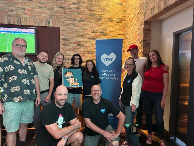 A group photo of the VeVe team posing indoors around a 'Start your collecting journey today' banner, with one person holding a framed cartoon character artwork.