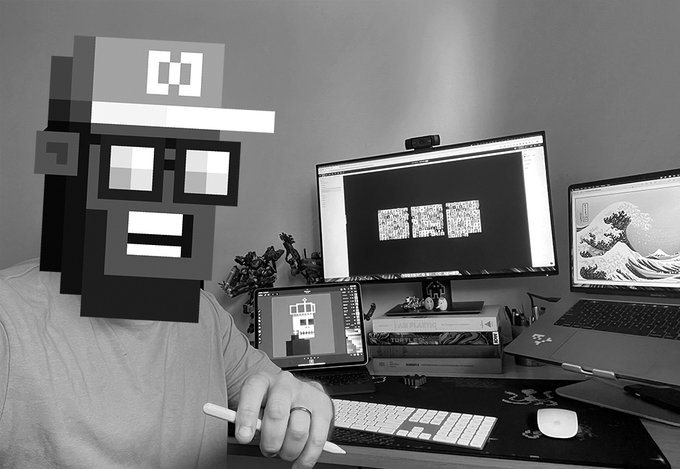 A person wearing a pixelated mask sits at a desk featuring a tablet displaying a character design, a monitor showing pixel art, and a laptop displaying "The Great Wave off Kanagawa," illustrating the digital pixel artistry of NFT creator ShiloniousMonk.