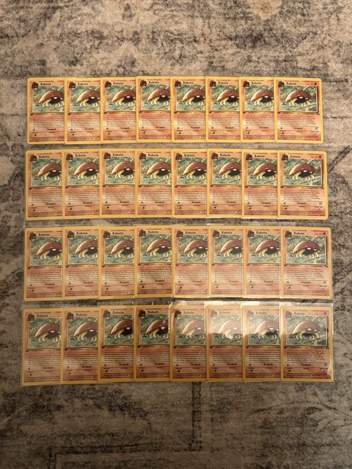 Multiple rows of Pokémon Kakuna trading cards displayed on a granite countertop.