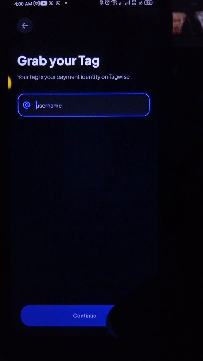 The image shows a phone screen displaying a payment app called Tagwise, which allows users to tag payments for specific transactions. The phone's screen is lit up with blue text that reads "Grab your Tag." There are two buttons visible on the screen - one labeled "Continue" and another labeled "TagIdentity," both of which are essential for using the app effectively. The background of the image is dark, making it difficult to read any additional information or details about the app's features.