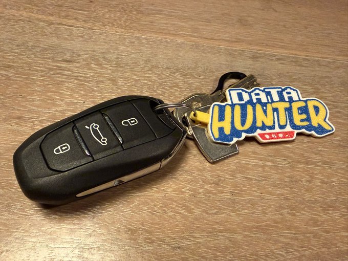 A set of car keys resting on a wooden surface, attached to a "DATA HUNTER" keychain with Chinese characters beneath the text. The image visually represents the "@datahuntersol" project as referenced in the post.